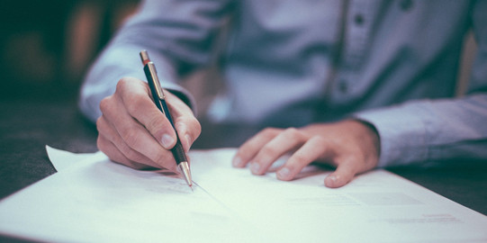 Person schreibt mit einem Stift auf Papier